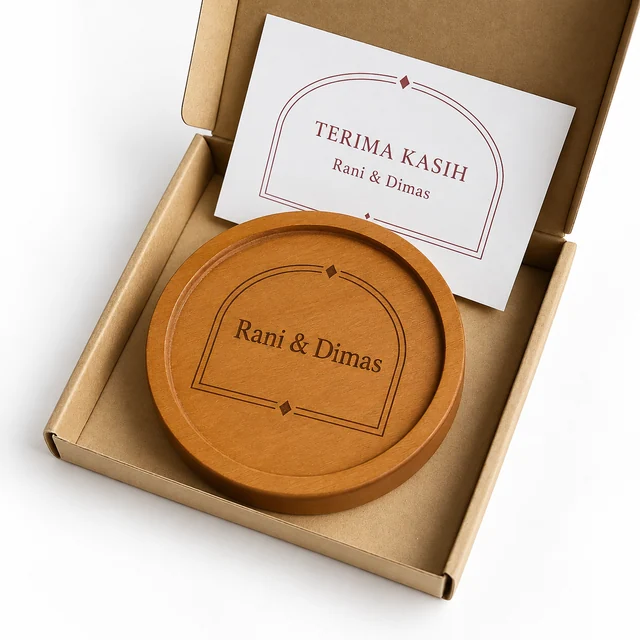 Tatakan kayu bergrafir Rani & Dimas dalam box kraft terbuka dengan kartu ucapan putih beraksen burgundy.
