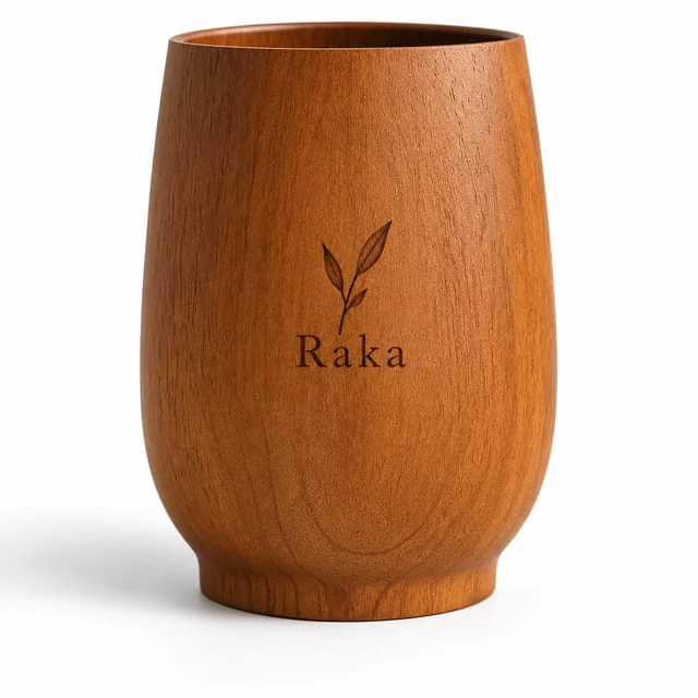 Detail gelas kayu Soma dengan grafir daun dan nama Raka pada latar putih.